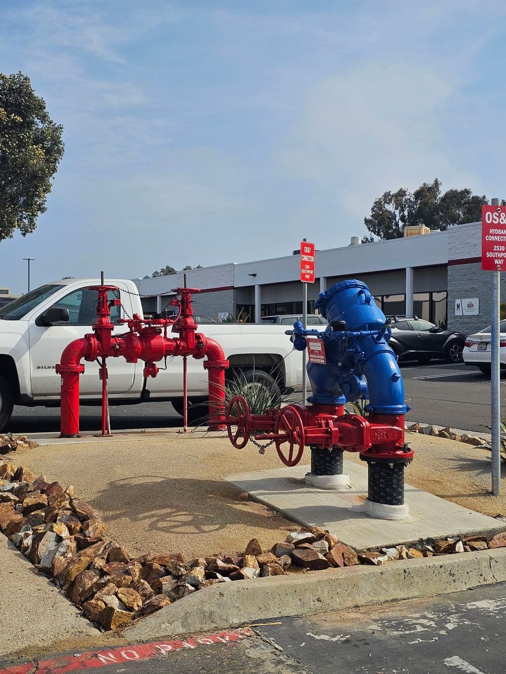 Red and blue fire hydrant system installed on a concrete platform with signage.