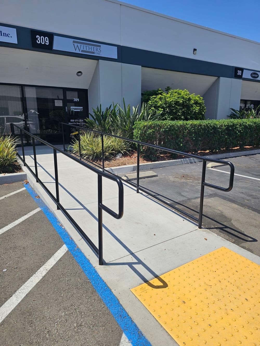 Accessible ramp leading to the entrance of Withers Inc. at 309, featuring safety rails.